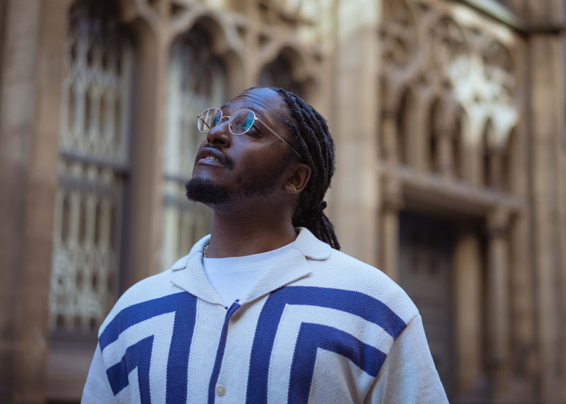 Image of Jay Chambers wearing a patterned sweater standing in front of an architectural building